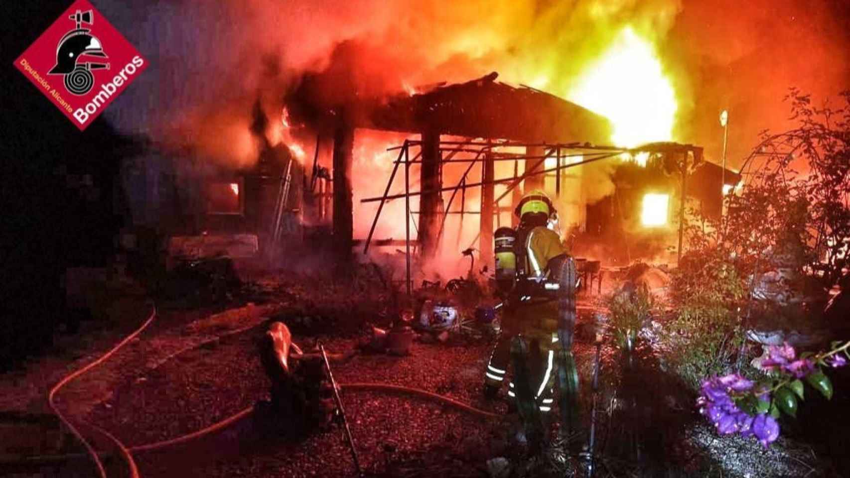 Un bombero apagando las llamas de la cabaña.