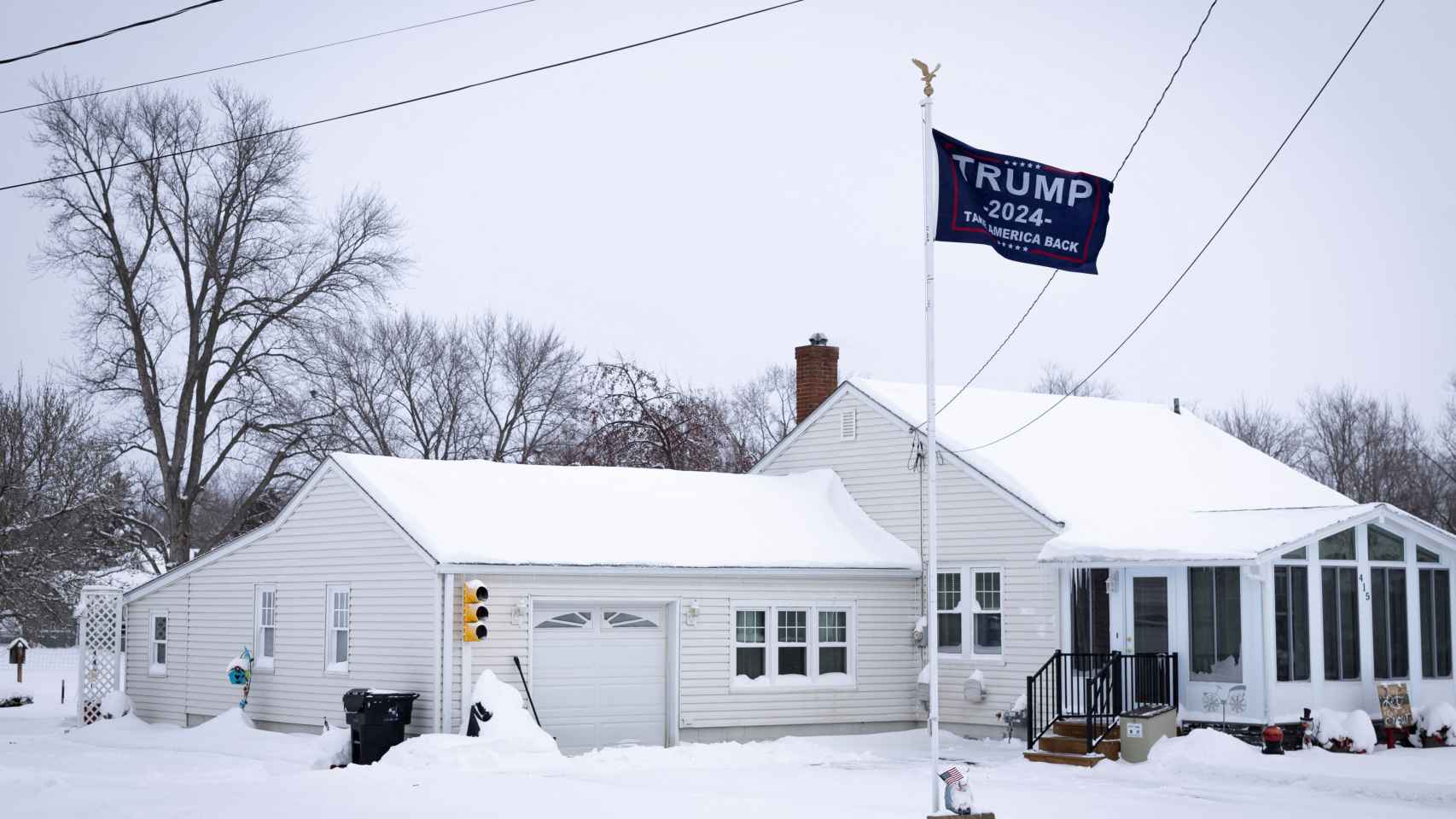 Una vivienda nevada en Iowa, con la bandera de campaña de Trump en el jardín