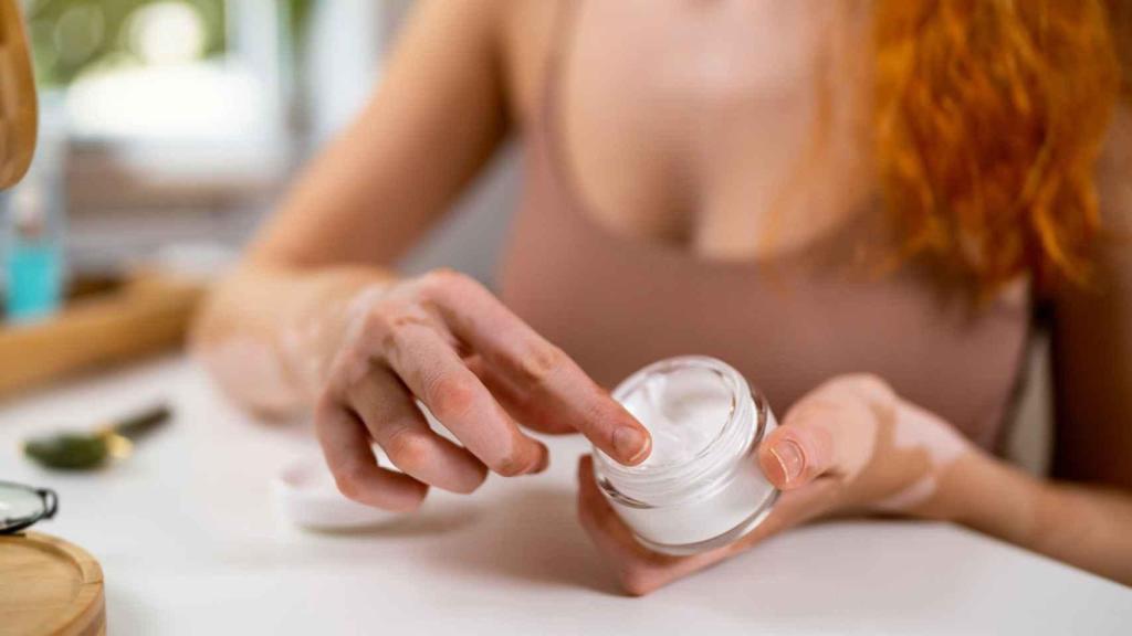 Una mujer echándose crema hidratante.