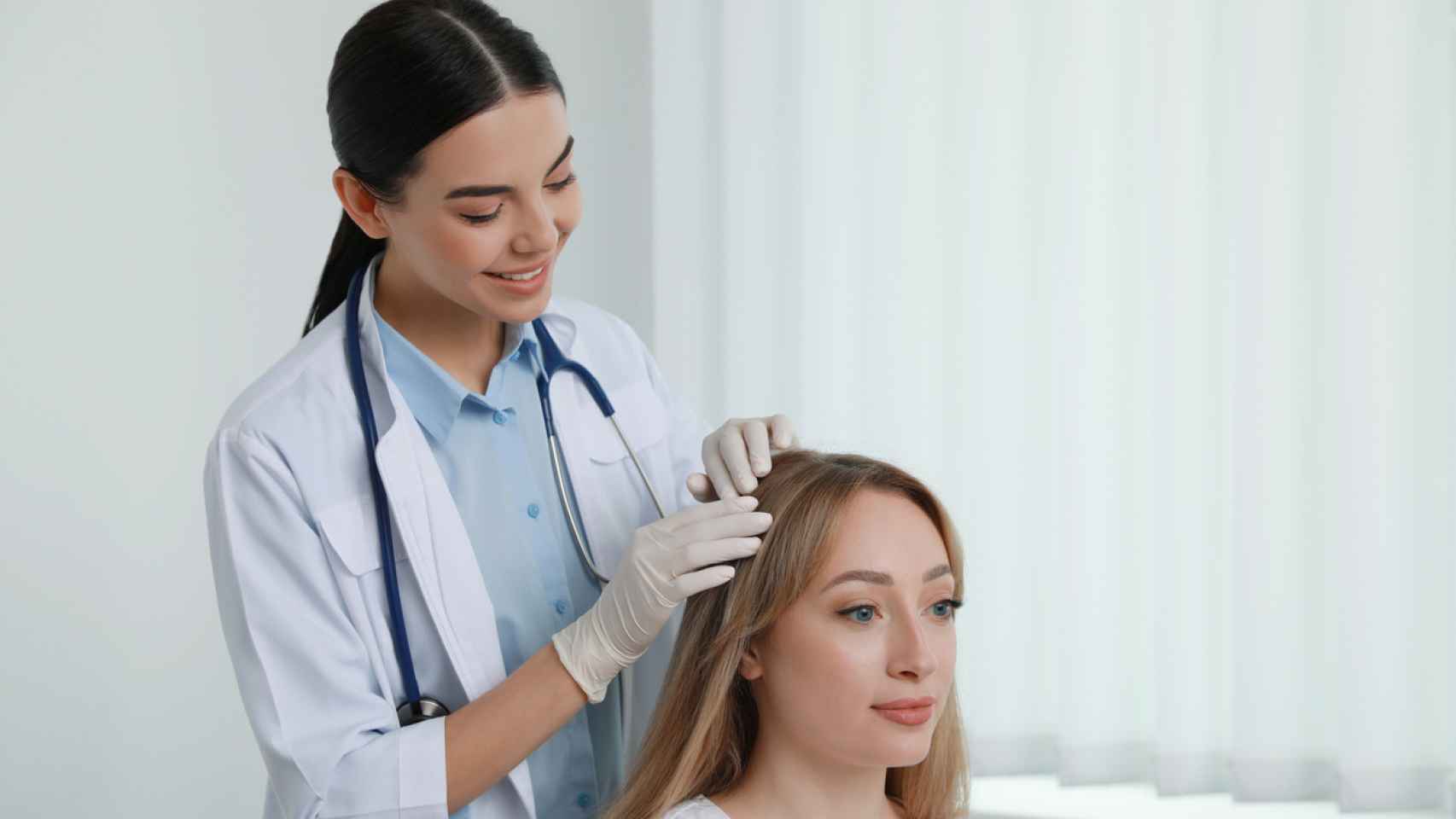 Una doctora examinando el cuero cabelludo de su paciente.