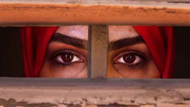 Una refugiada mira por el marco de una ventana para representar la situación carcelaria de las mujeres en Afganistán.