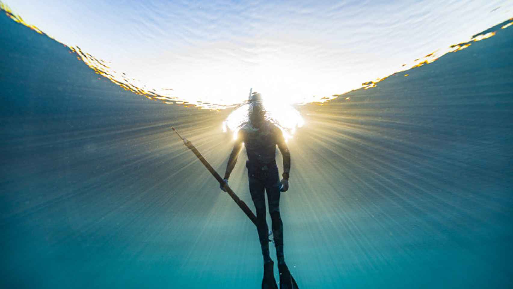 Imagen de un pescador submarino, explorando y cazando peces en el océano azul profundo