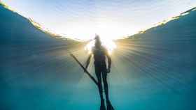 Imagen de un pescador submarino, explorando y cazando peces en el océano azul profundo