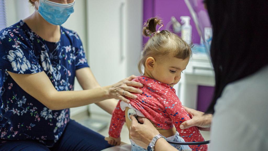 Una joven es observada por la pediatra.