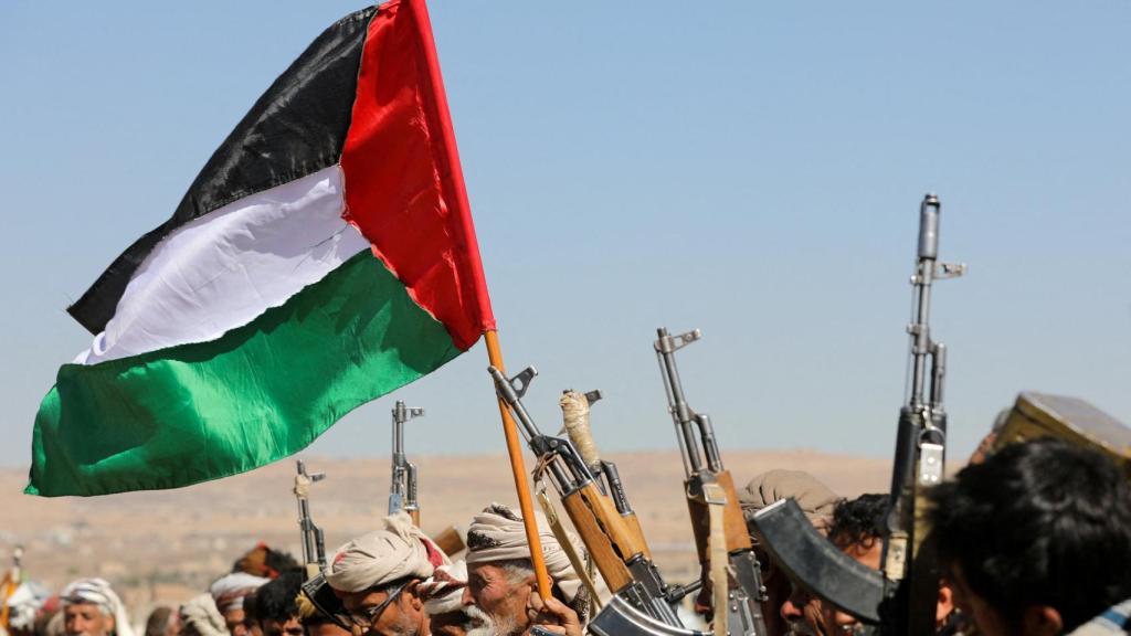 Partidarios de los hutíes de Yemen ondean una bandera palestina y sostienen sus armas de fuego.