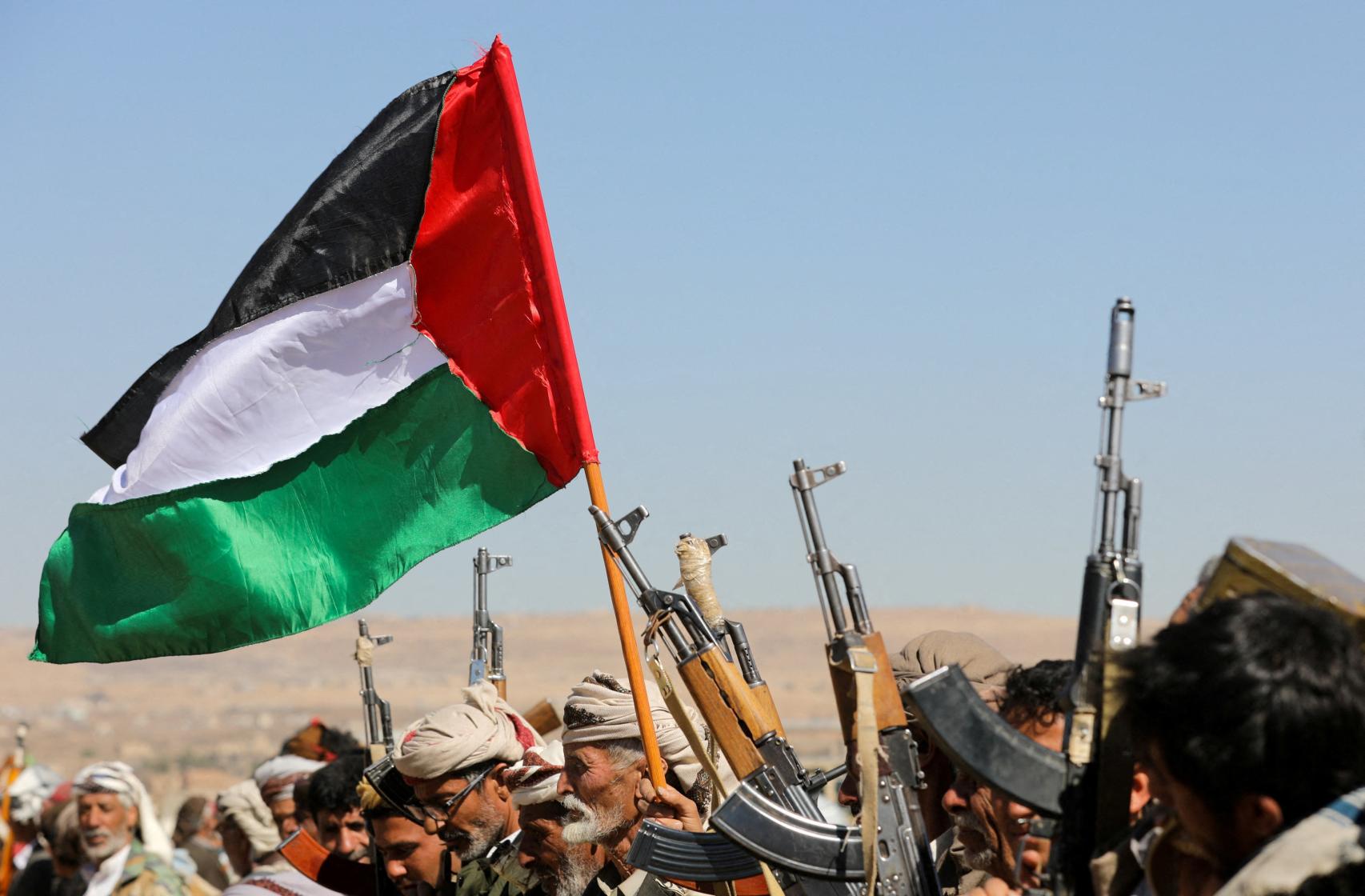 Partidarios de los hutíes de Yemen ondean una bandera palestina y sostienen sus armas de fuego.