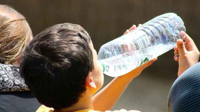 Un niño bebe agua embotellada.