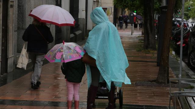 Varias personas caminan bajo la lluvia.