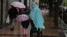 Varias personas caminan bajo la lluvia.