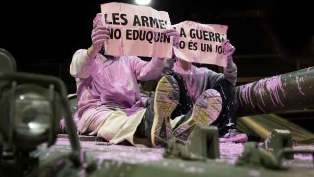 Momento de la protesta en el que dos antimilitaristas tiñeron de rosa un tanque del Ejército en Expojove. EE