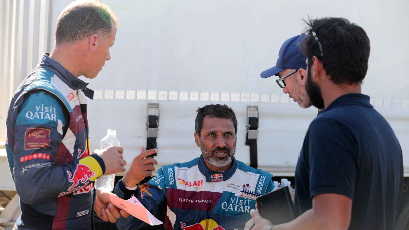 Nasser Al-Attiyah y su copiloto Mathieu Baumel discutiendo con miembros de equipo en el Rally Dakar 2024