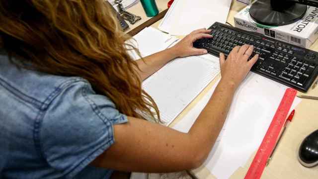 Una mujer escribe en el teclado de su ordenador, en una oficina.