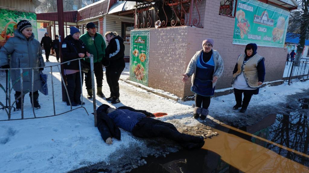 La gente se reúne cerca del cuerpo de una víctima después del ataque militar ucraniano en un mercado de alimentos