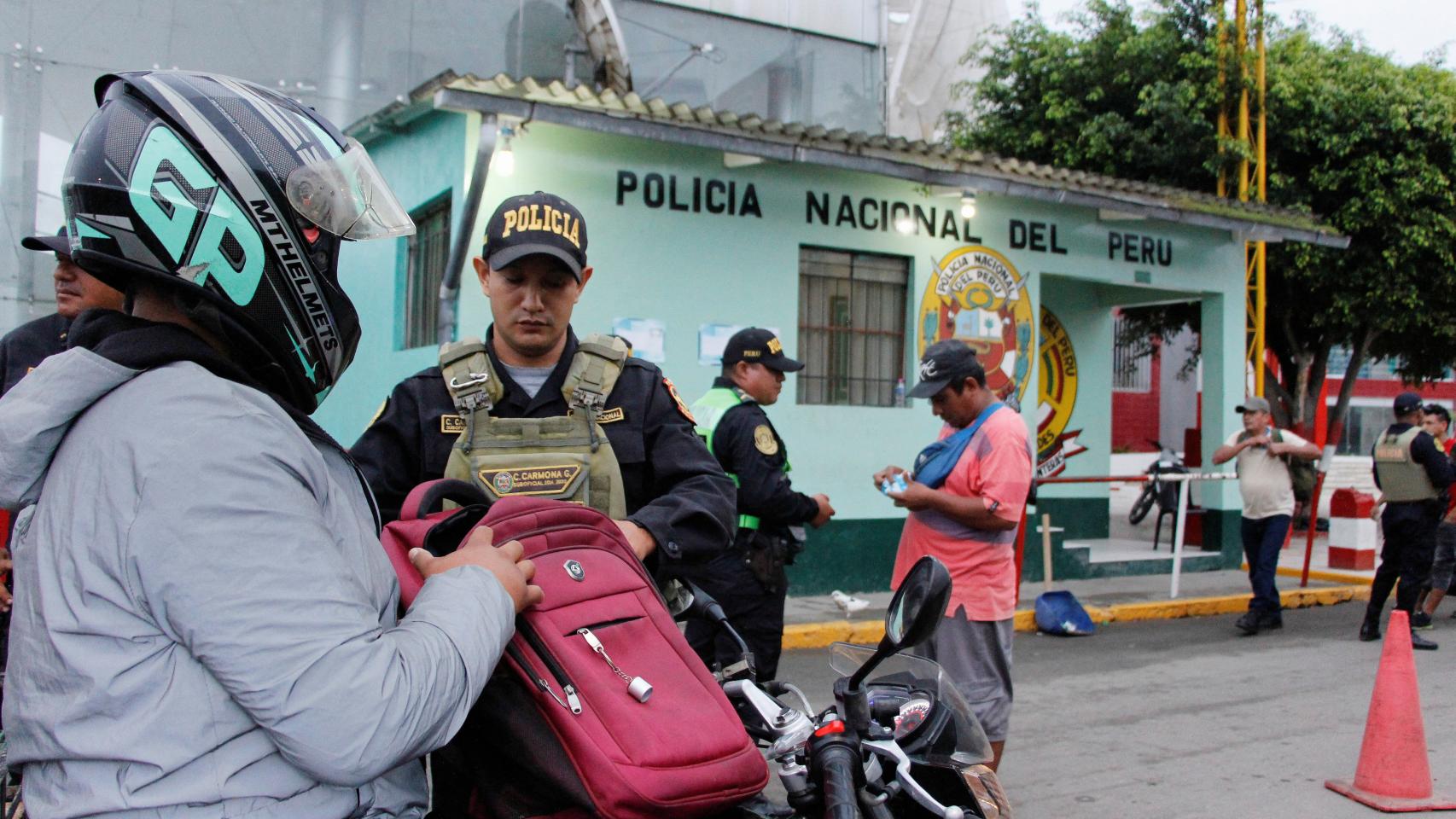 Un policía peruano comprueba la identificación de un hombre procedente de Ecuador.