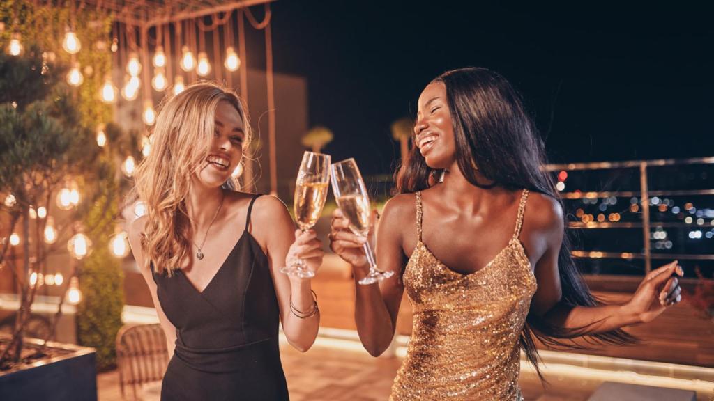 Dos mujeres con 'dress code' 'black tie' durante una fiesta.