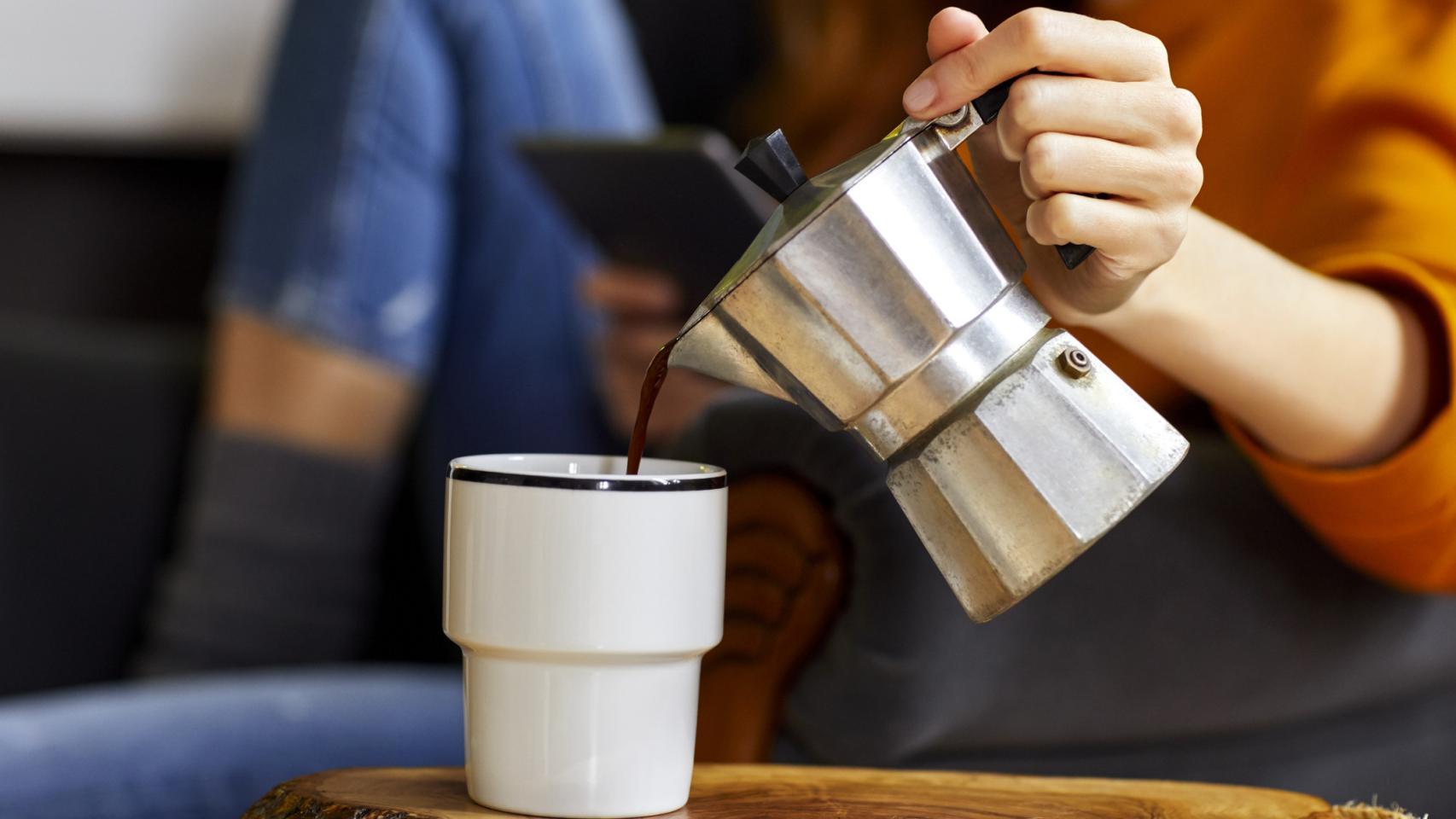 Una persona echa café en una taza.