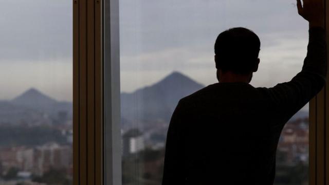 Imagen de archivo de un hombre mirando por la ventana.