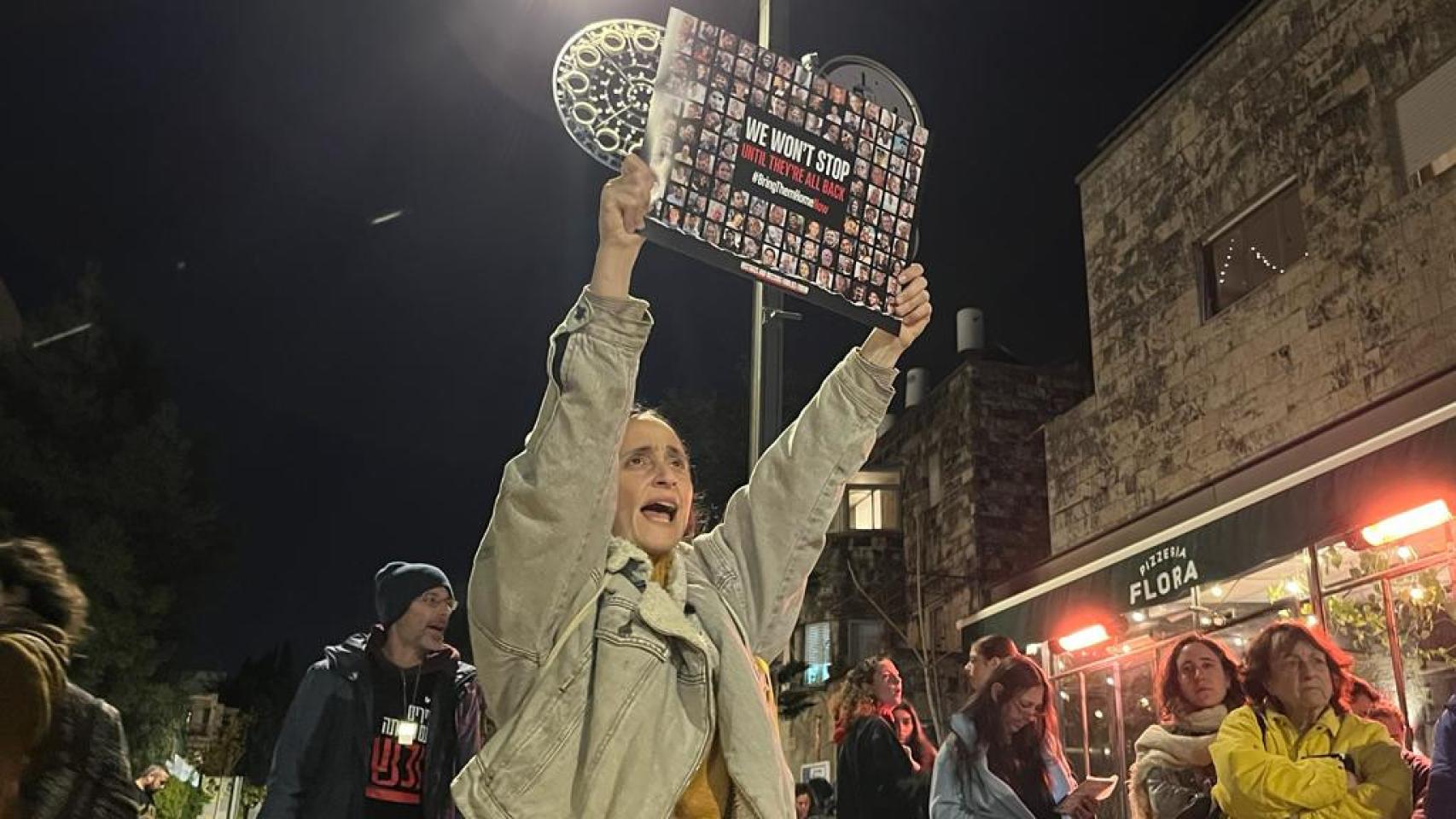 Una manifestante sostiene un cartel con fotos de rehenes que reza: No pararemos hasta que vuelvan.