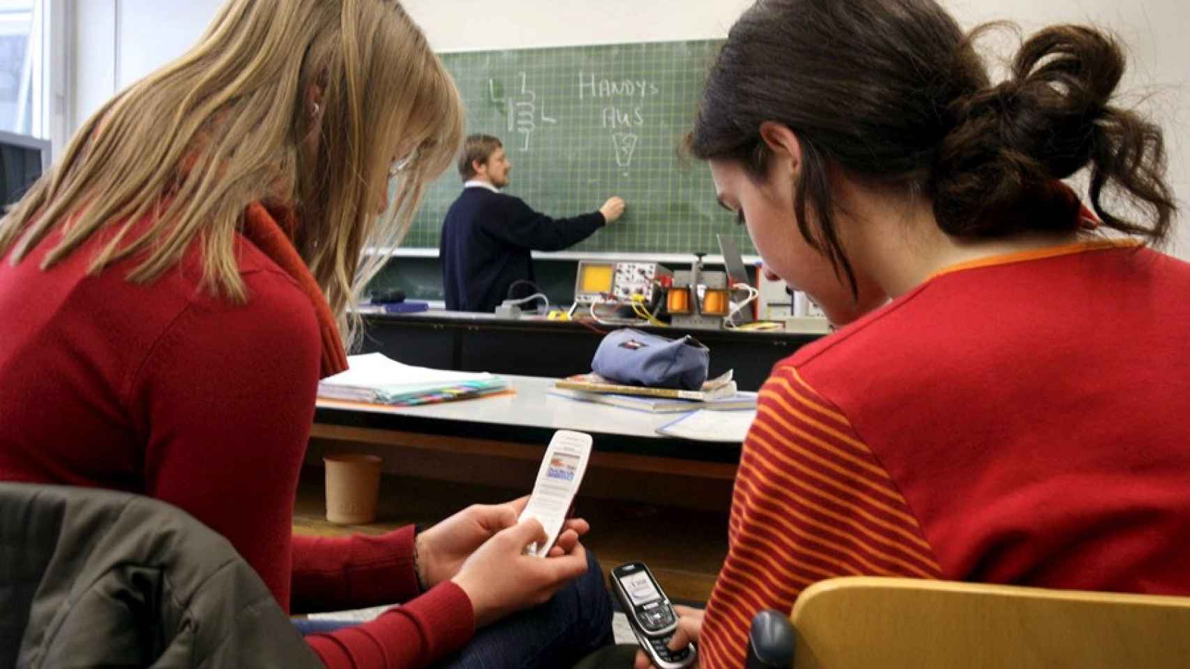 Dos alumnas usan sus móviles en el aula.