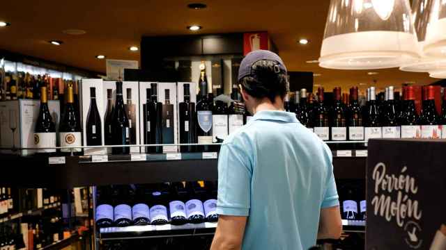 Un hombre mira la sección de vinos de un supermercado.