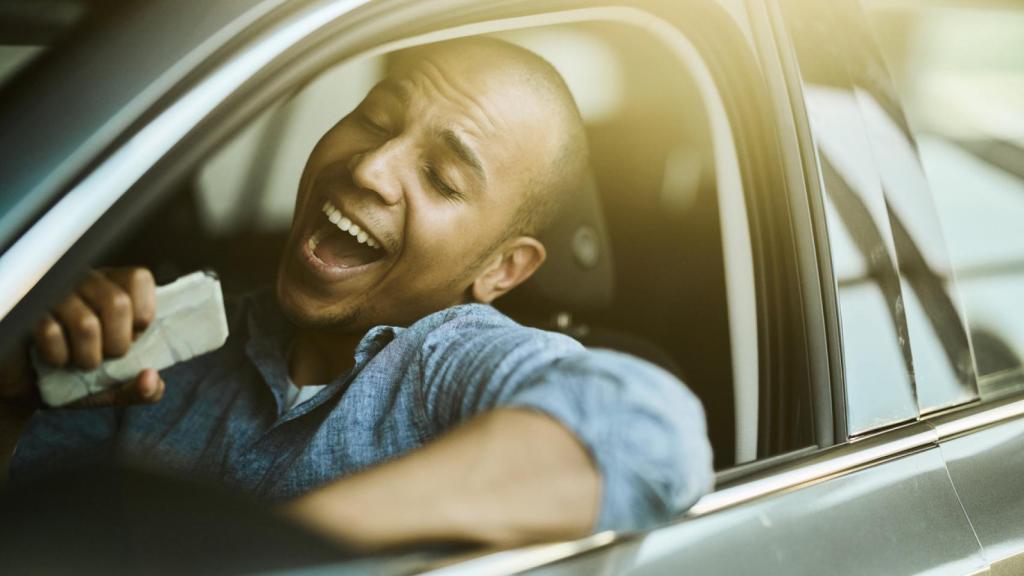 Hombre  cantando mientras conduce un coche