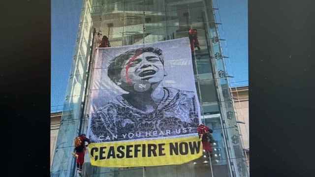 Activistas de Greenpeace cuelgan una pancarta pidiendo un 'alto el fuego ya' en el Museo de Arte Reina Sofía.
