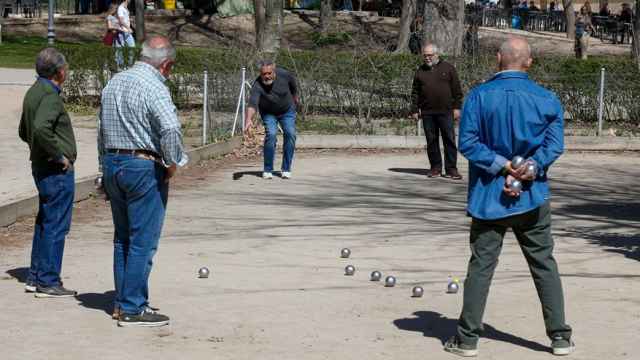 Un grupo de jubilados jugando a la petanca en un parque.