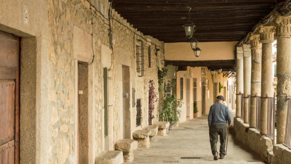 Imagen de una persona mayor caminando por un pueblo.