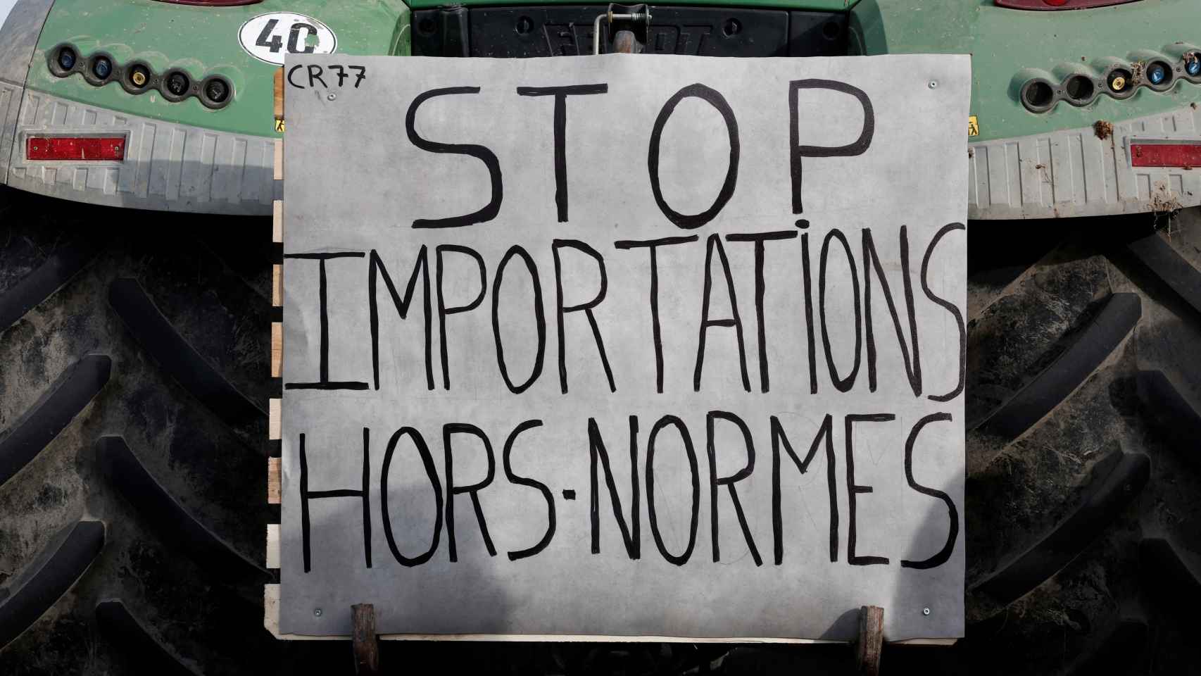 Un cartel cuelga en la parte trasera de un tractor: Detener las importaciones no estandarizadas.