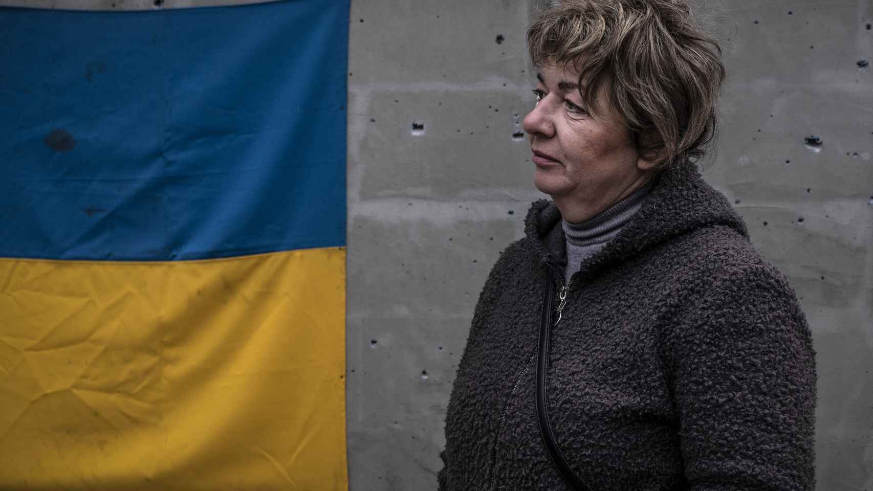 Una mujer ucraniana junto a la bandera que ha colocado en la fachada de su casa, en el norte de Járkov.