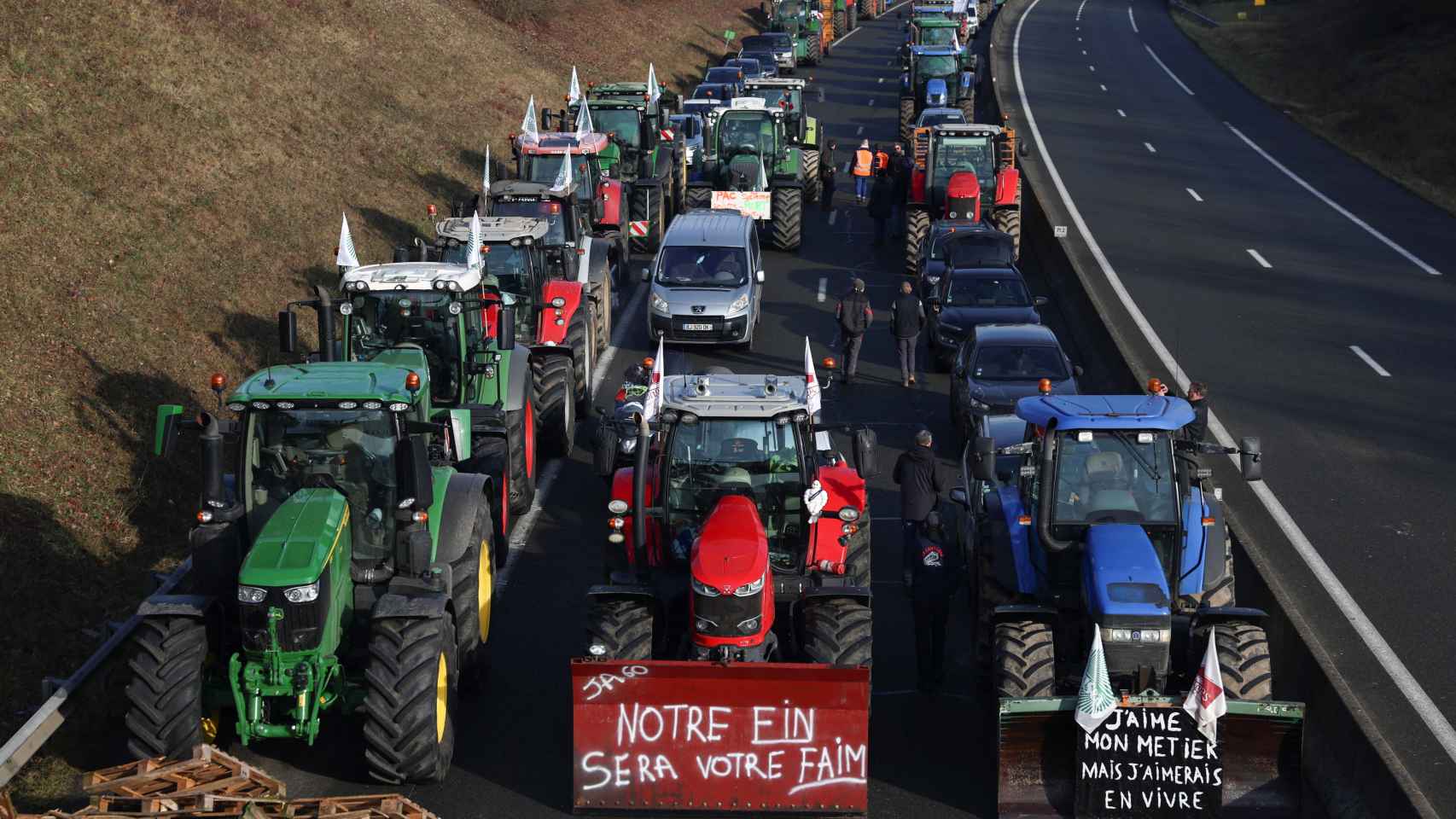 Una fila de tractores bloquea la A16 a la altura de Beauvais. Uno de ellos dice: Nuestro fin será vuestra hambre.