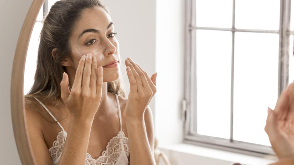 Una mujer aplicándose crema en el rostro.