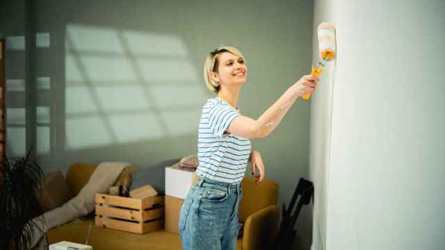 Mujer pintando la pared de su casa.