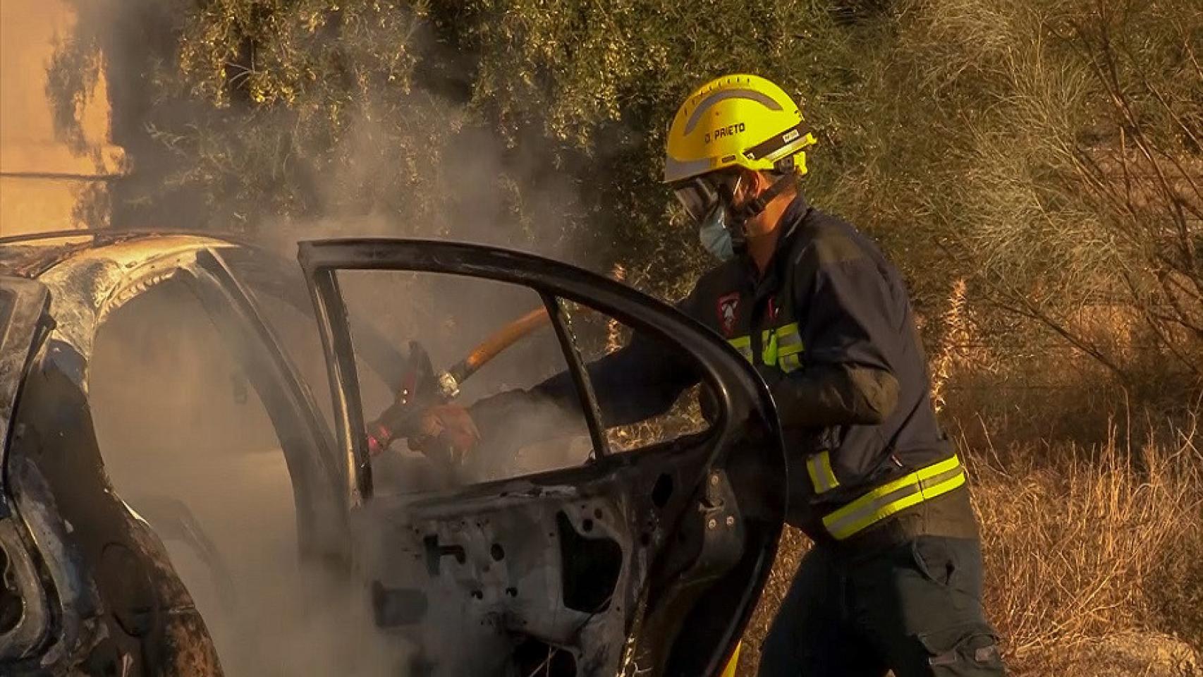 Imagen de un bombero sofocando un incendio en un vehículo.