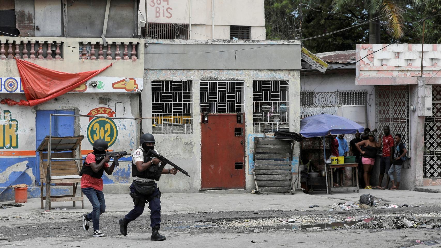 Varias personas se repliegan en una esquina de Puerto Príncipe durante el atraco a una comisaría.