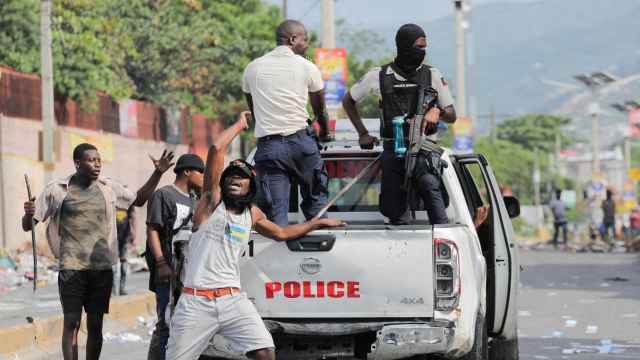 Un manifestante anima las protestas detrás de un coche de la Policía haitiana.