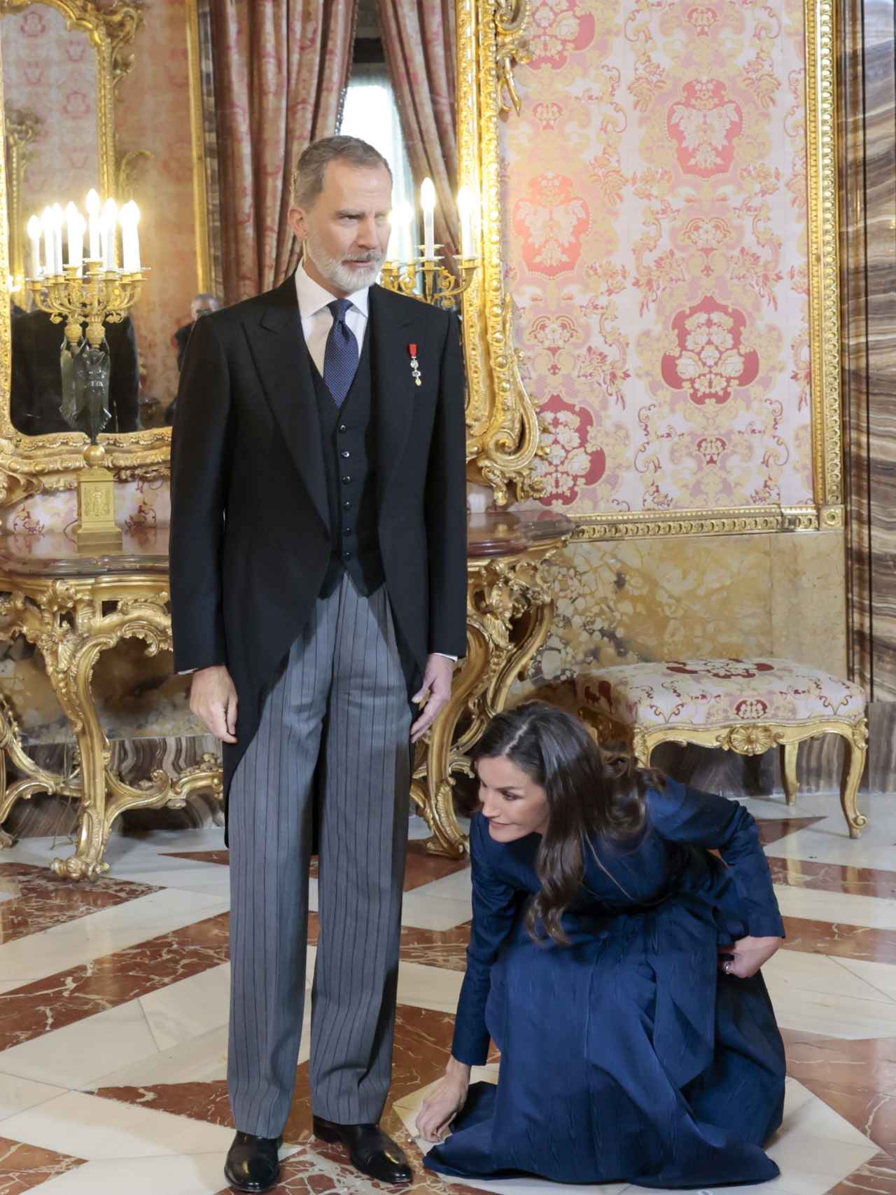 La reina Letizia no duda en agacharse en el momento en que termina de saludar a los asistentes al Palacio Real.