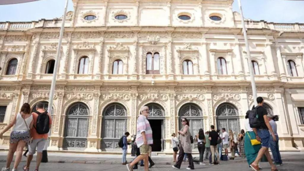 Sevillanos pasean ante el Ayuntamiento.