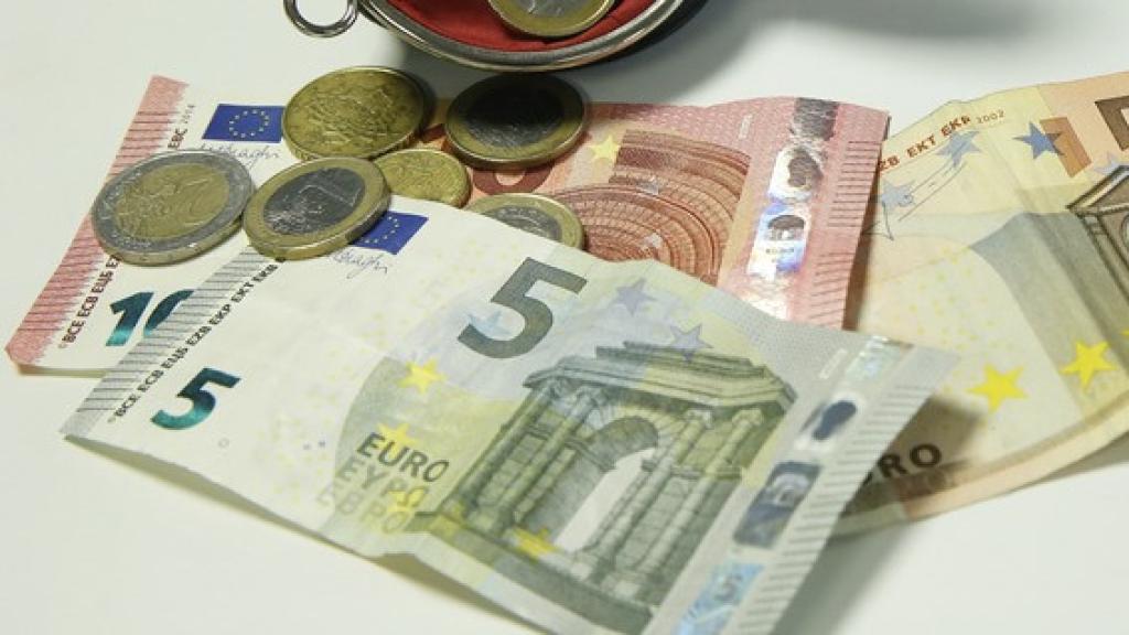 Imagen de archivo de varios billetes y monedas en un monedero.