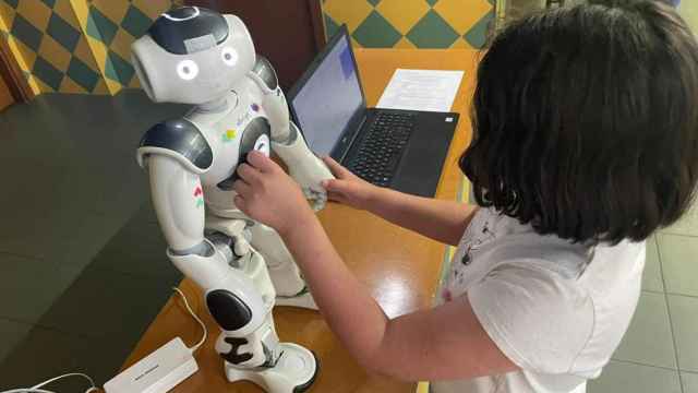 Una niña juega con Nao, el robot asistente.