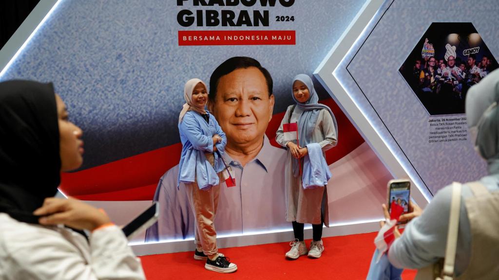 Simpatizantes posan para hacerse fotos delante de un cartel de Prabowo Subianto  en Yakarta, Indonesia, 2 de febrero de 2024.
