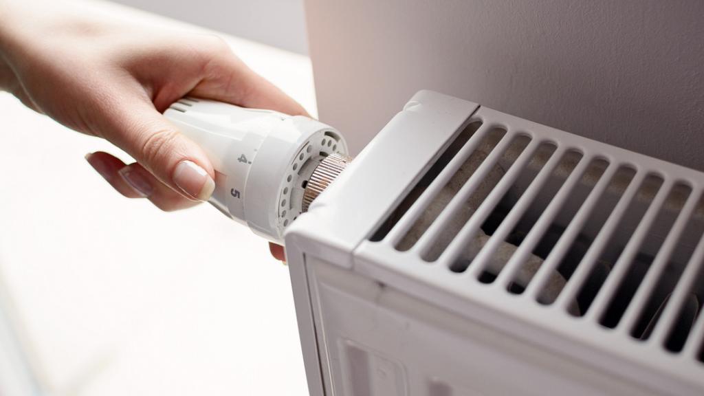 Una persona manipula el termostato de un radiador.