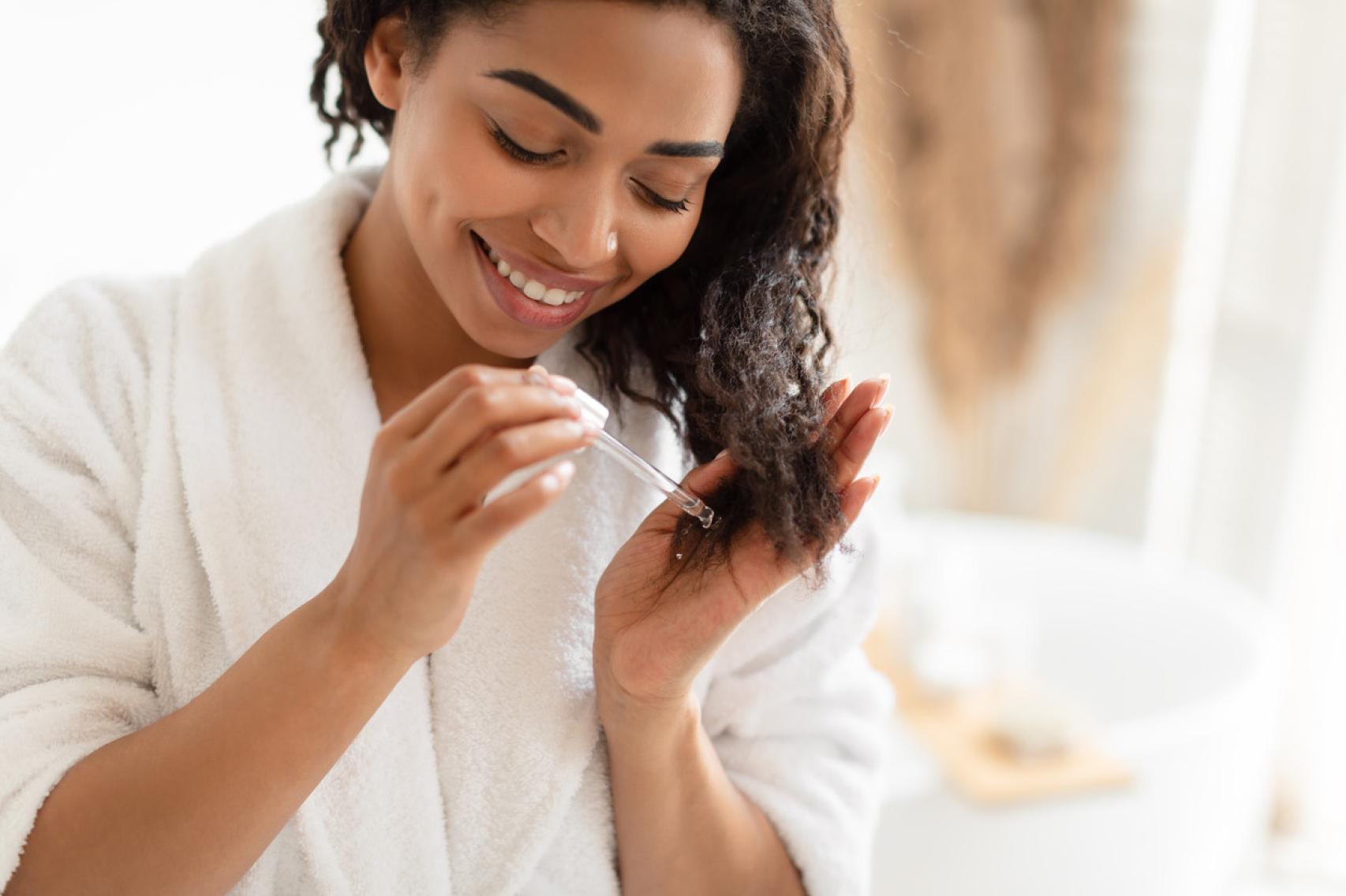 Imagen de mujer aplicando aceite en su cabello.