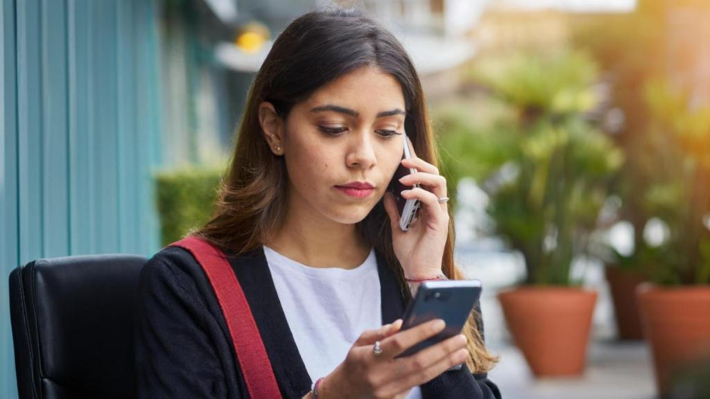 Una mujer chatea mientras habla por teléfono