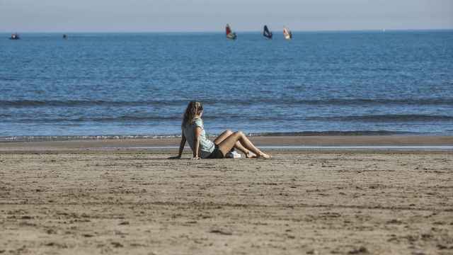 Una mujer sentada en la arena de la playa de la Malvarrosa, a 25 de enero de 2024.