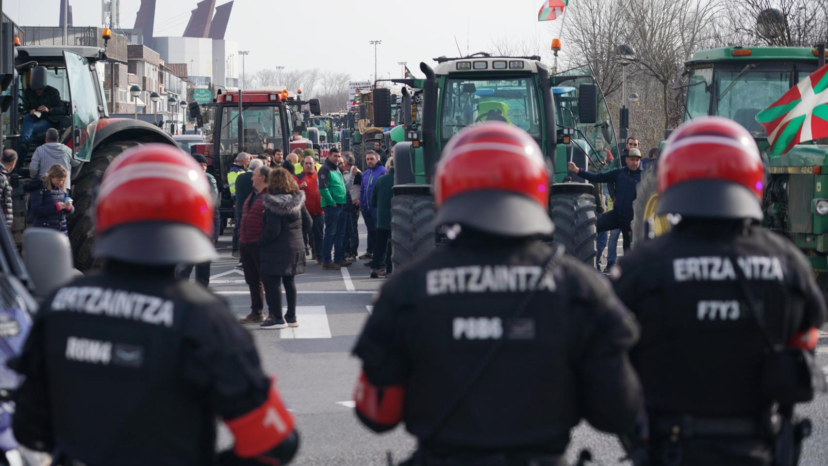 Agentes de la Ertzaintza delante de los tractores y agricultores en la segunda jornada de protestas.