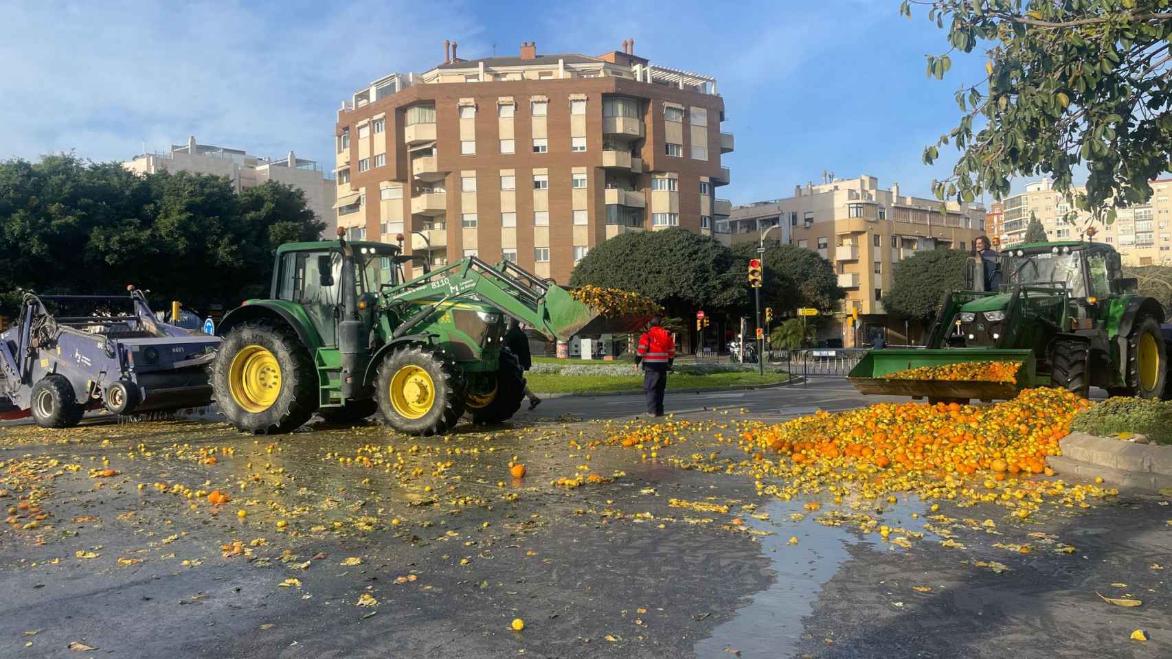 Equipos de limpieza del Ayuntamiento de Málaga recogen las naranjas y limones que dejaron los agricultores anoche.