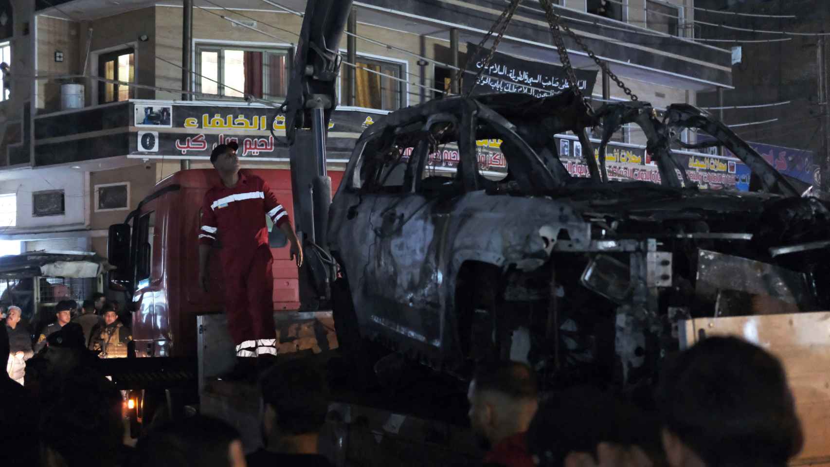 Las autoridades iraquíes retiran el coche calcinado atacado por EEUU en el que presuntamente había un comandante de Hezbolá.