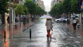 Sevillanos se protegen de la lluvia en la calle Asunción.