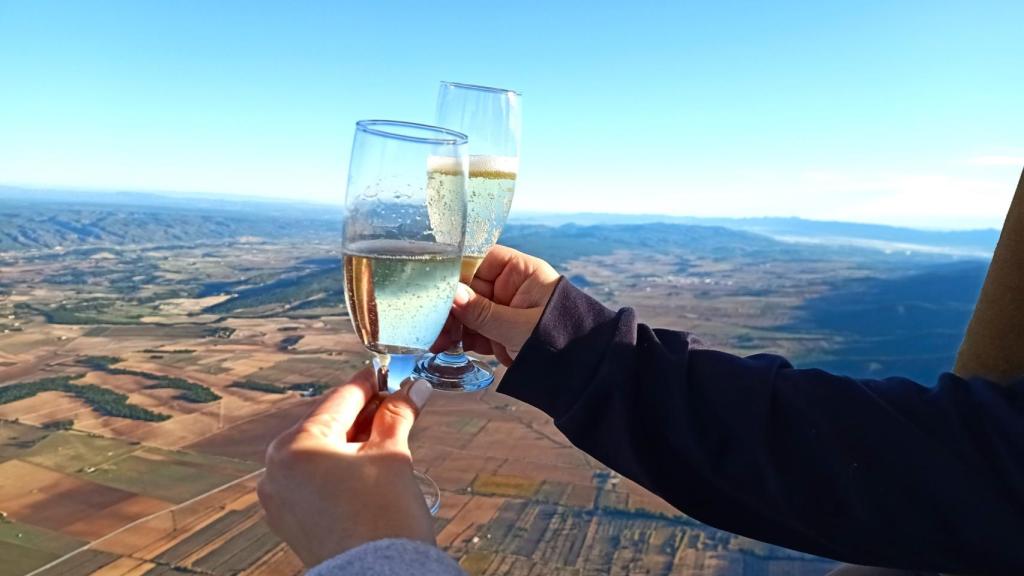 Dos personas brindan a bordo de un globo durante un vuelo.